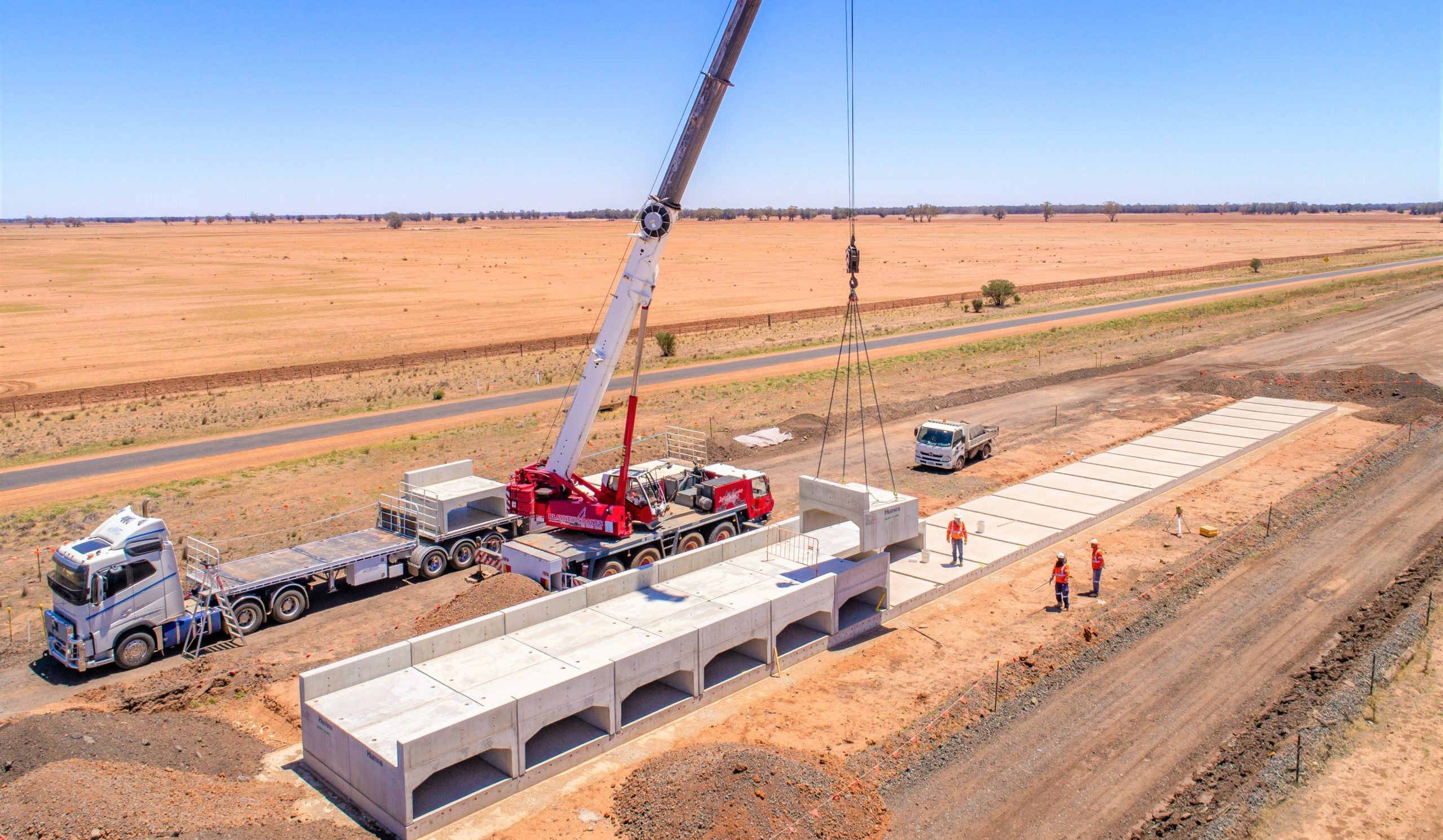 Concrete calverts are unloaded off a truck and installed by a crane, at a construction area on the Parkes to Narromine project