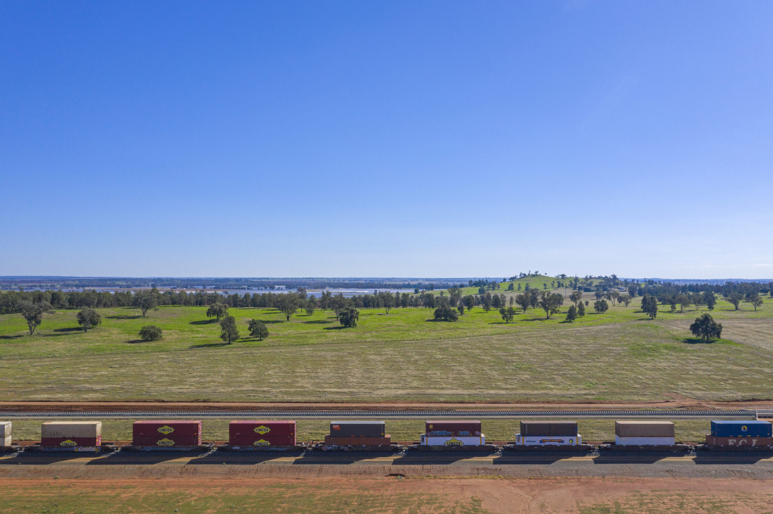 Aerial view of the double-stack container train travels through a rural area near Parkes, New South Wales.