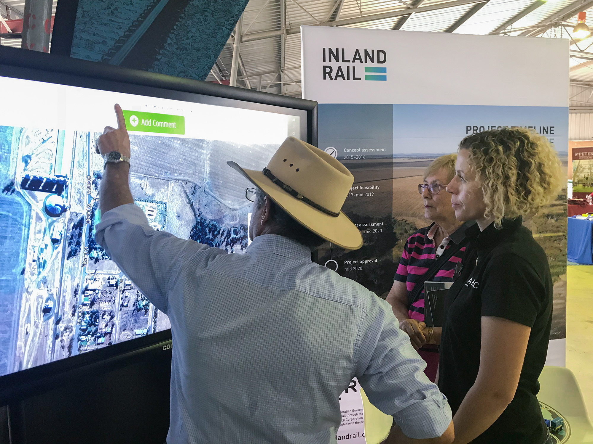 Inland Rail stakeholder engagement representative look at a interactive project map on a large screen at a community drop-in session