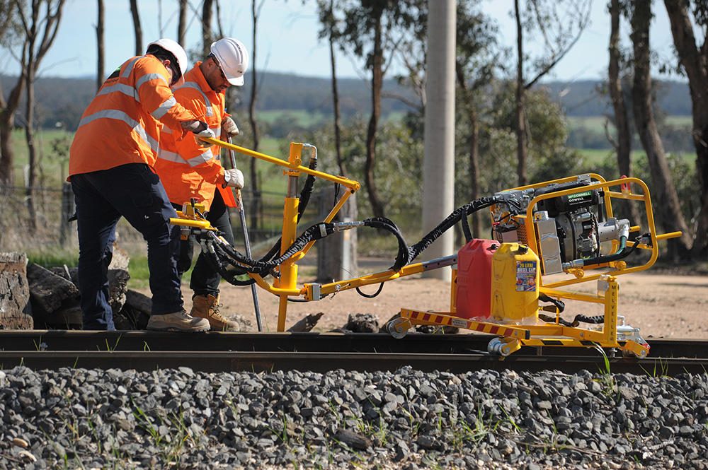 Image of track workers in PPE operating machinery on the rail track