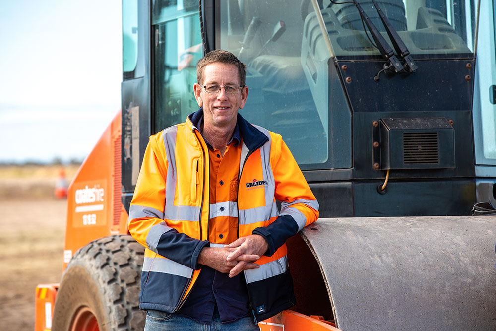 Local supplier standing with machinery needed to build Inland Rail.