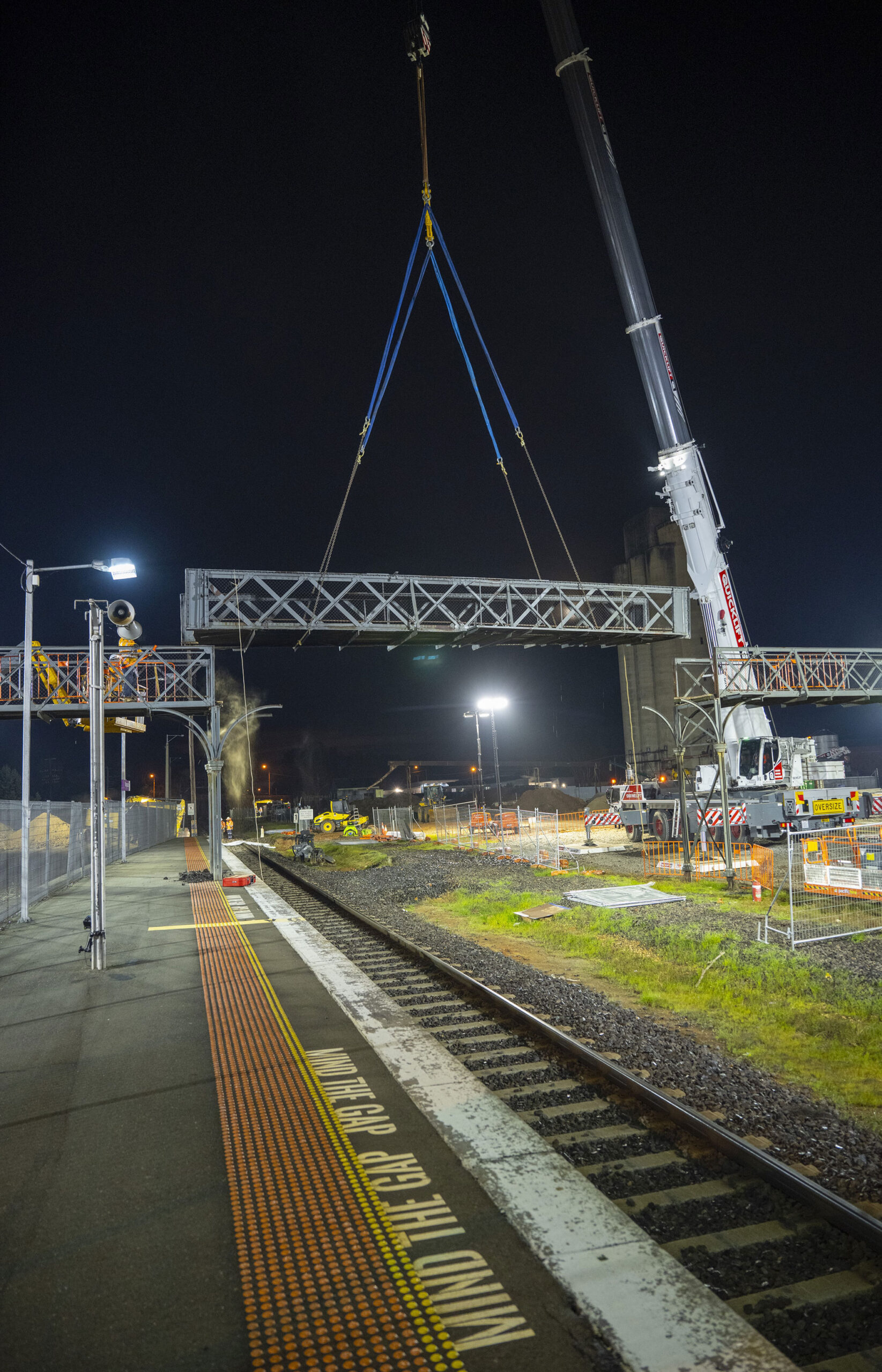 Cranes lift the centre section of the Cusack Street footbridge at Wangaratta in preparation for the new station underpass