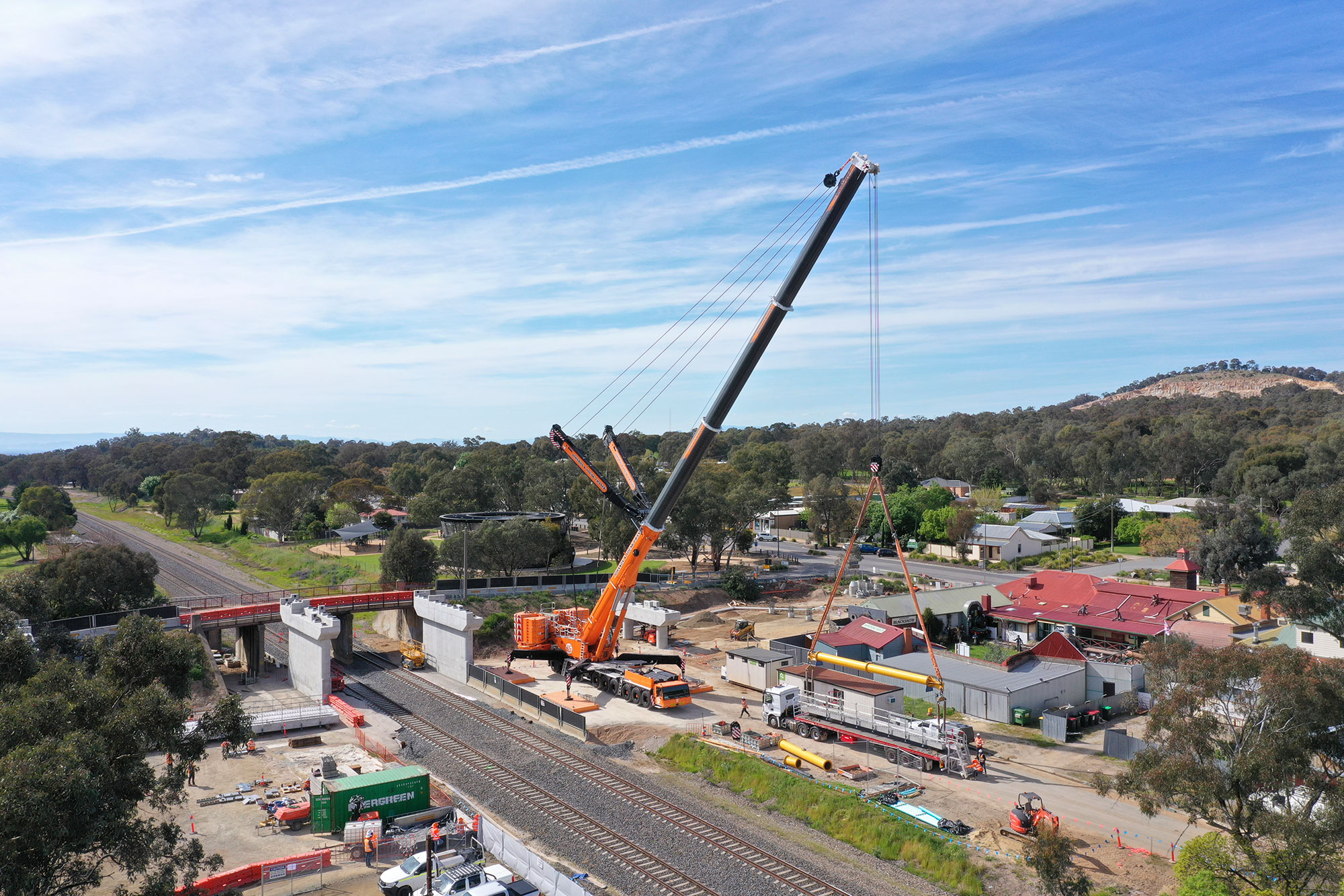 A crane unloads beams from the trucks